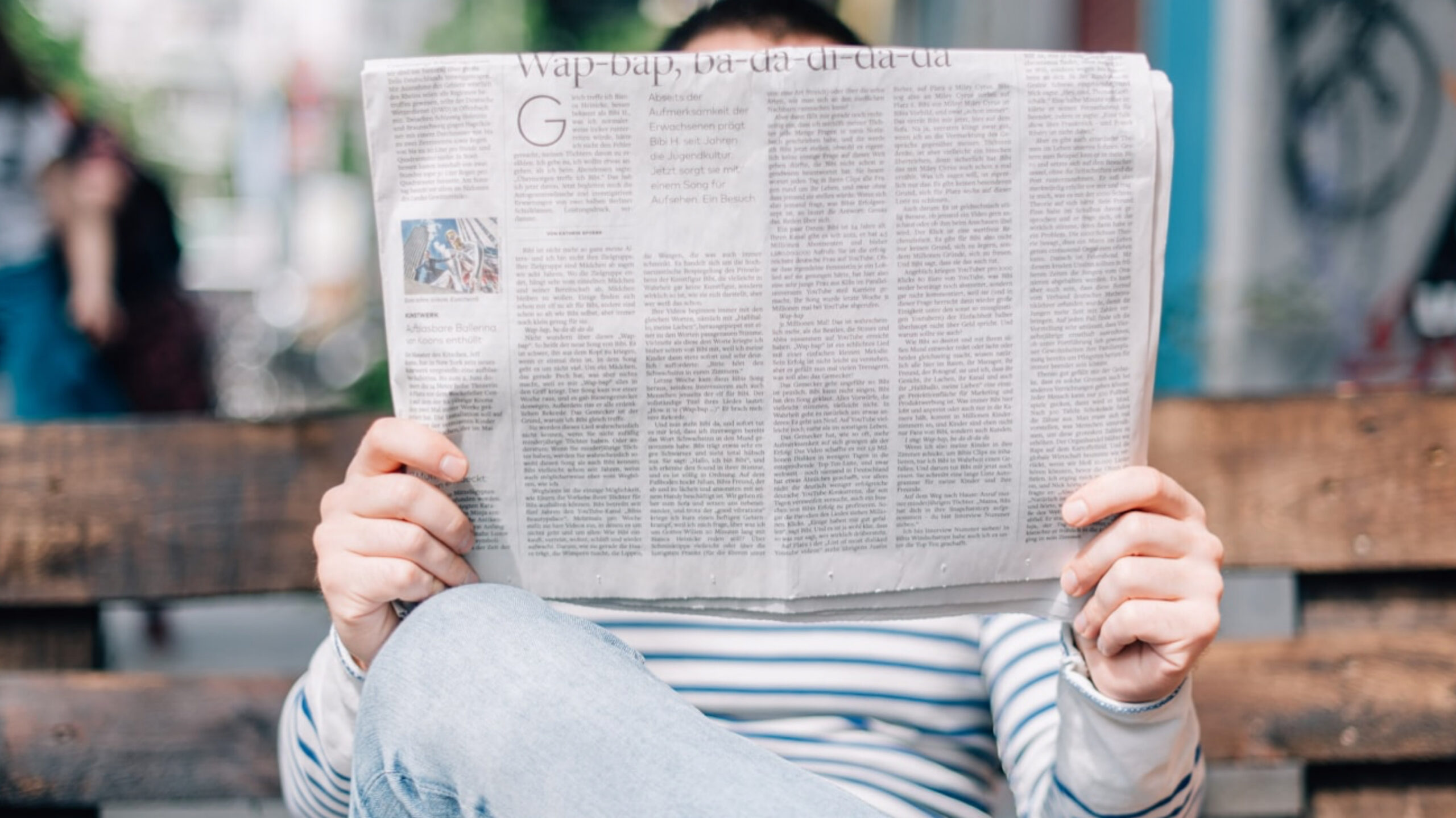 Person reading a physical newspaper outdoors representing everyday items fading out of use