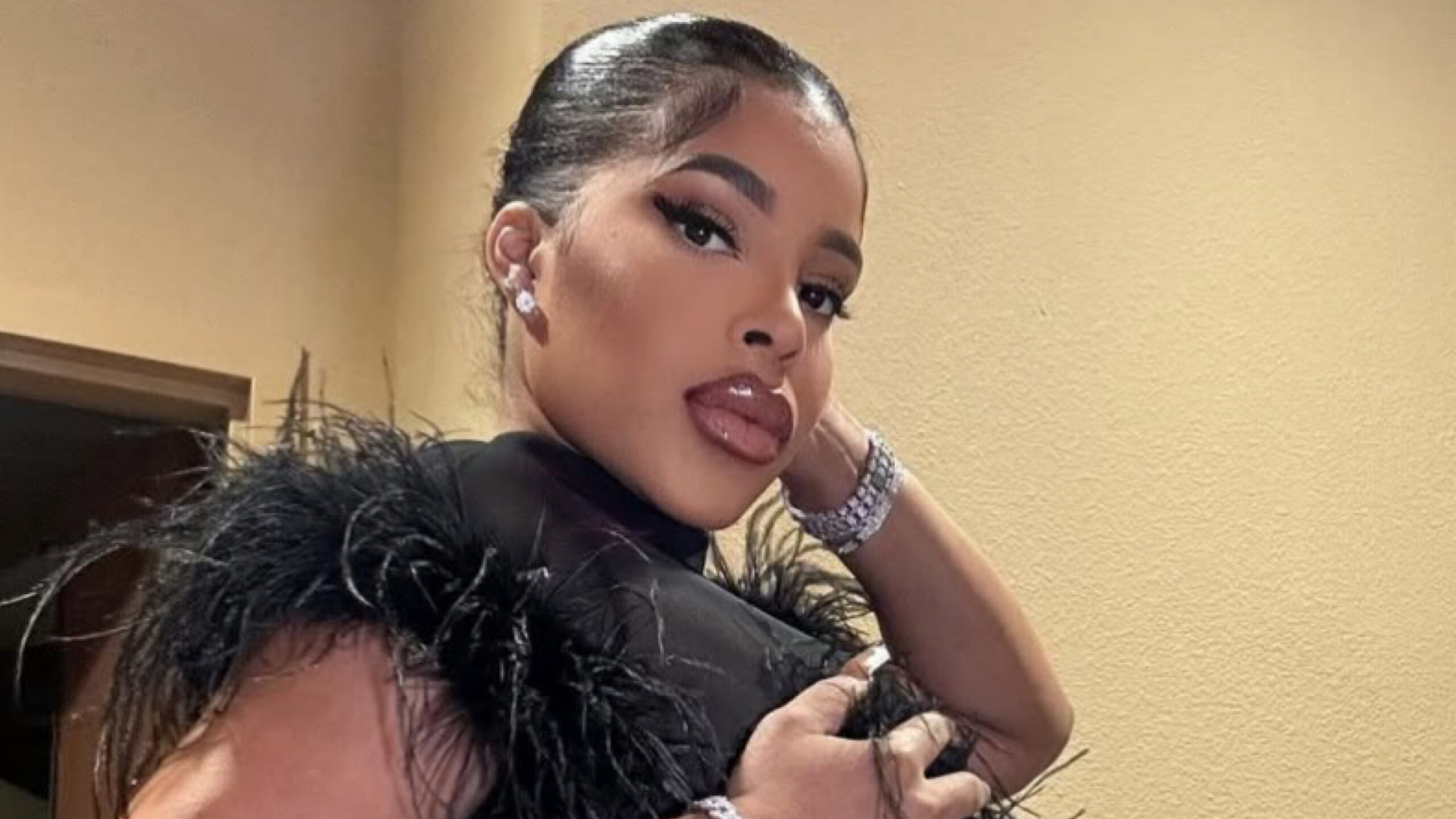 Ariela Meija Polanco known as Ariela La Langosta, poses in a feather trimmed black top with diamond Jewelry