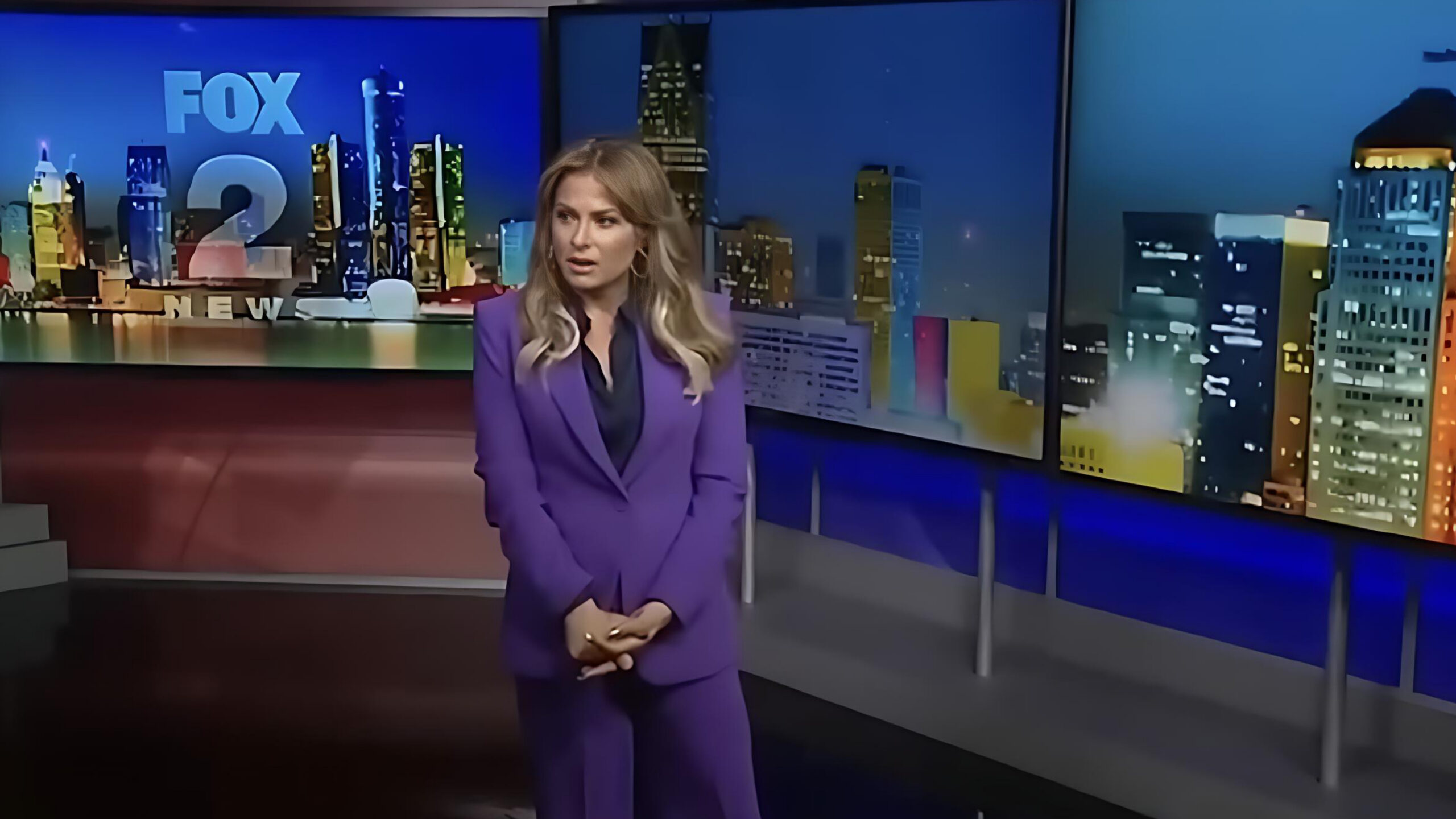 Fired Fox 2 Detroit anchor Taryn Asher stands in the studio wearing a purple pantsuit