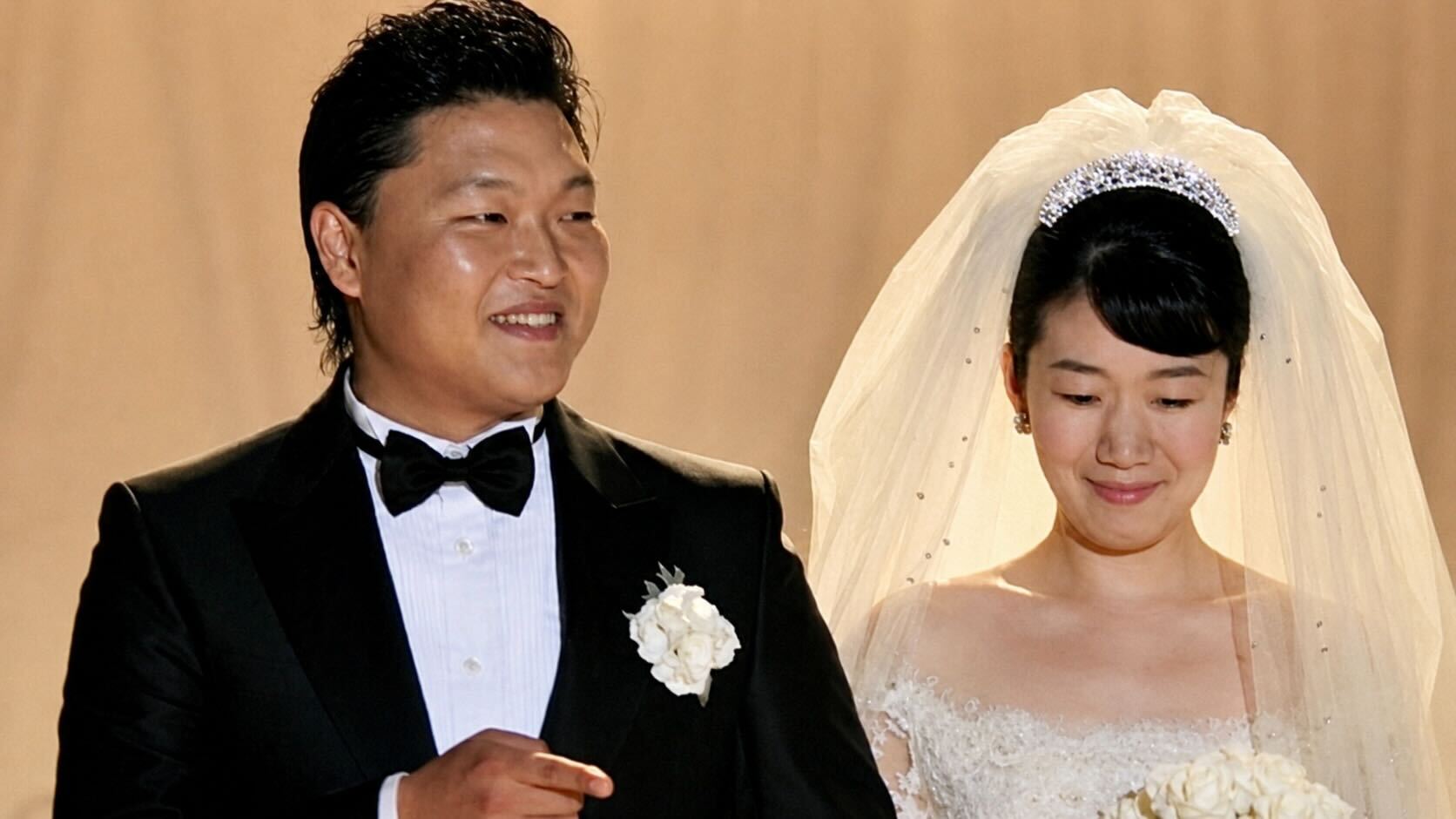 PSY and his wife Yoo Hye-yeon posing together at their wedding ceremony