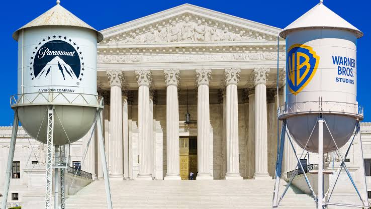 Composite image featuring the white neoclassical facade and columns of the U.S. Supreme Court building in the background. In the foreground, a water tower featuring the Paramount Pictures logo stands on the left, while a water tower with the Warner Bros. Studios logo stands on the right against a clear blue sky.