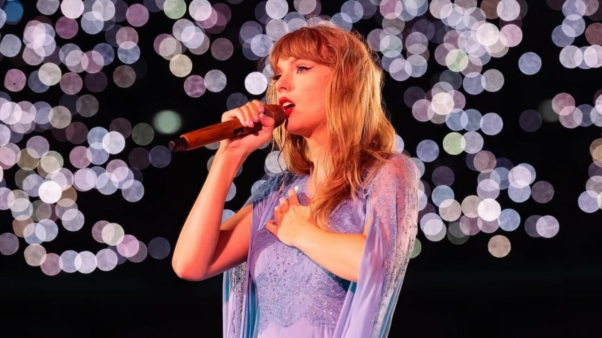 Taylor Swift performing on stage during The Eras Tour in a lavender gown.