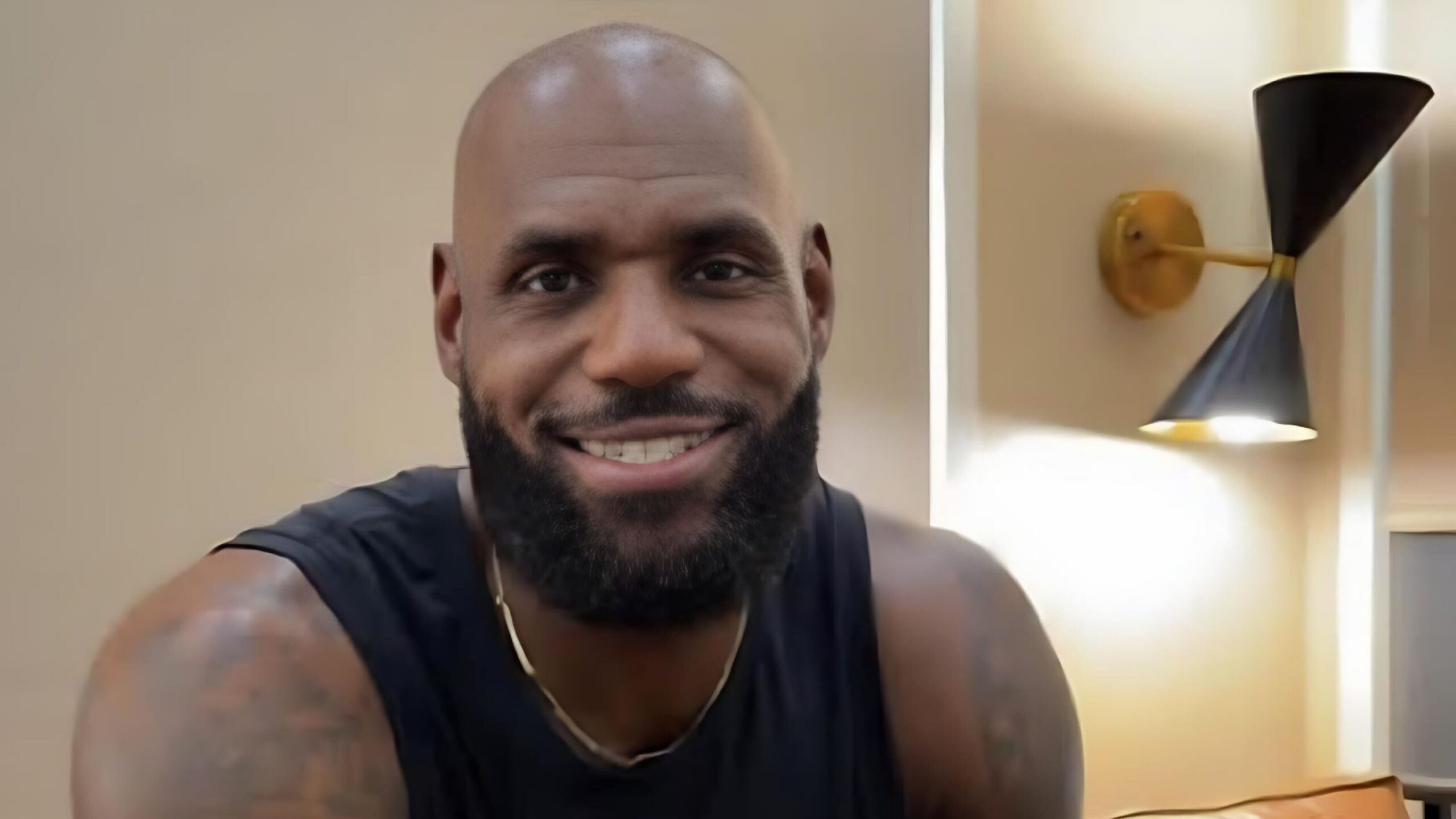 Basketball player LeBron James smiling directly at the camera indoors.